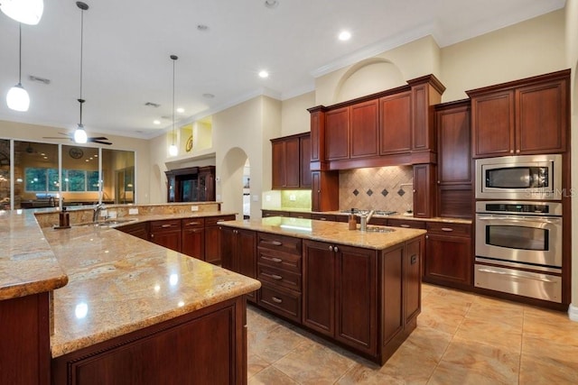 kitchen with light stone countertops, stainless steel appliances, tasteful backsplash, a spacious island, and pendant lighting