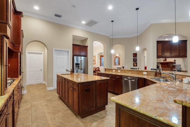 kitchen featuring light stone countertops, appliances with stainless steel finishes, sink, decorative light fixtures, and a large island