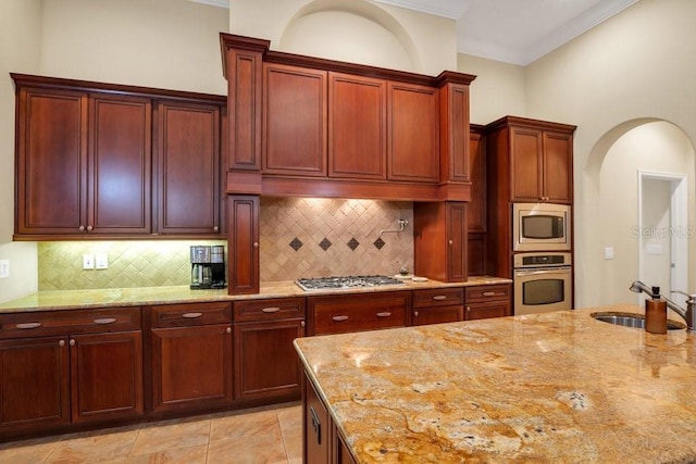 kitchen with decorative backsplash, sink, stainless steel appliances, and light stone counters