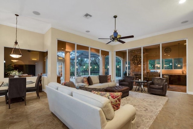 living room with a fireplace, ceiling fan, crown molding, and light tile patterned floors