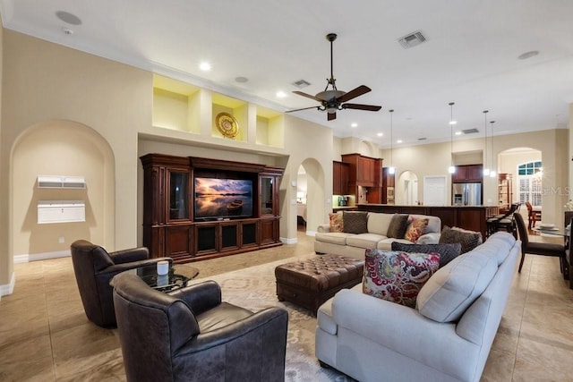 tiled living room with built in shelves, ceiling fan, and ornamental molding