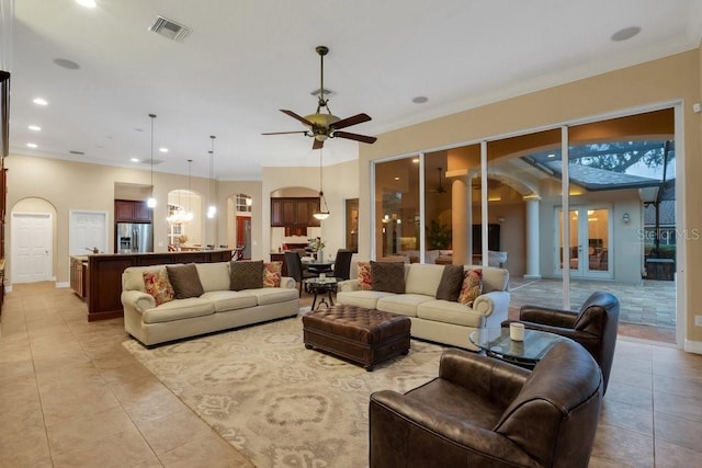 living room with ornate columns, light tile patterned floors, ceiling fan with notable chandelier, and ornamental molding