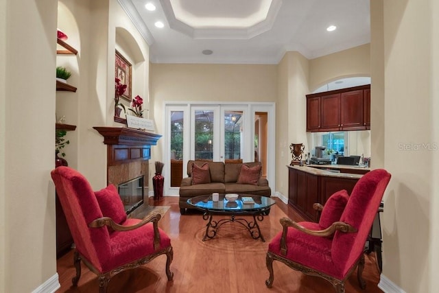 living room with french doors, a raised ceiling, light hardwood / wood-style flooring, a high end fireplace, and ornamental molding