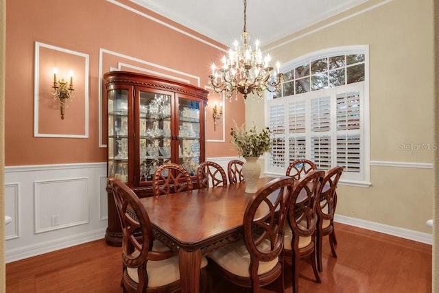 dining area featuring crown molding, wood-type flooring, and a notable chandelier