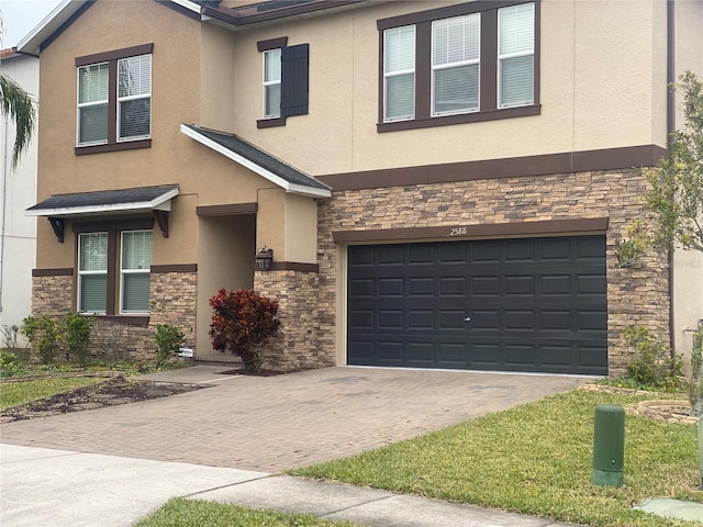 view of front facade with stone siding, decorative driveway, and stucco siding