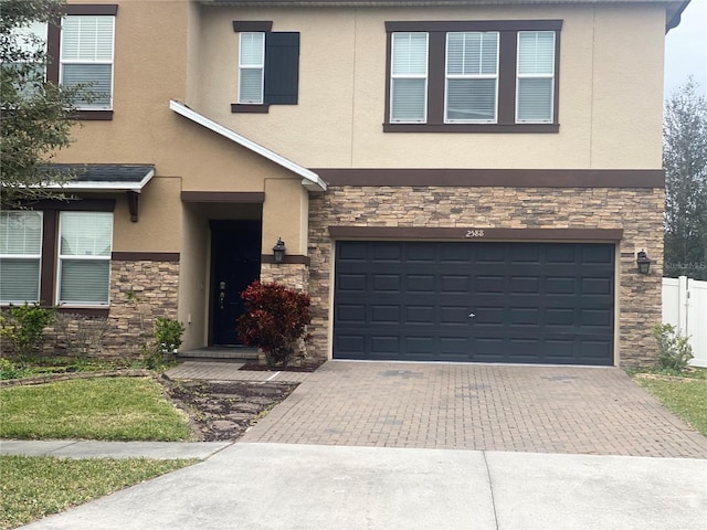 view of front of home with stone siding, decorative driveway, an attached garage, and stucco siding