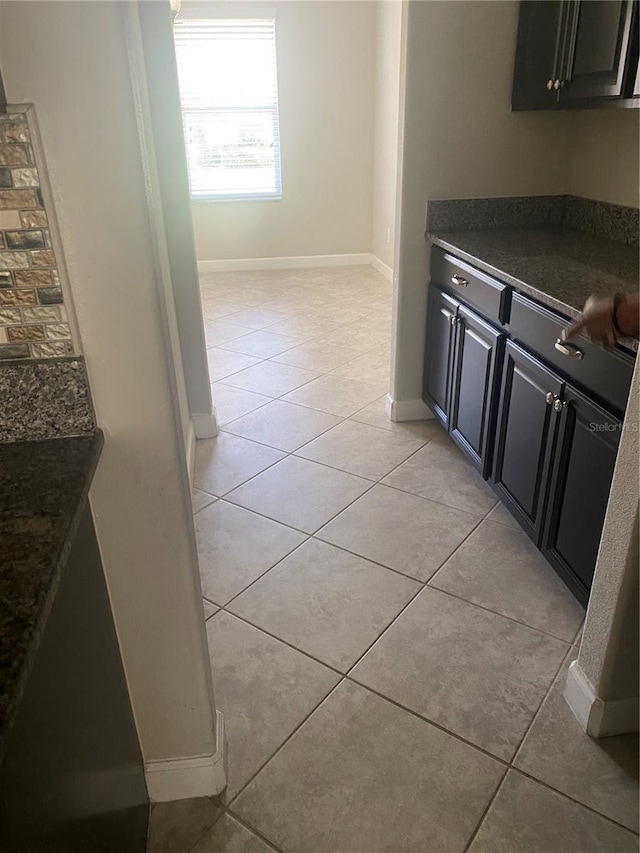 kitchen with dark countertops, light tile patterned floors, baseboards, and dark cabinets