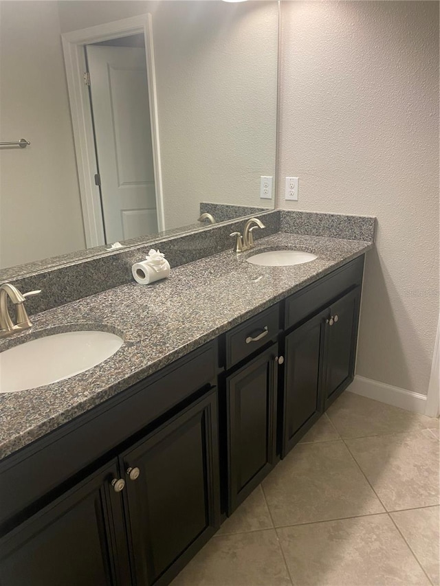 bathroom featuring tile patterned flooring, a sink, baseboards, and double vanity