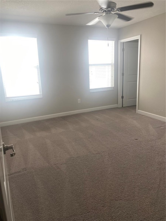 empty room with carpet, ceiling fan, and baseboards