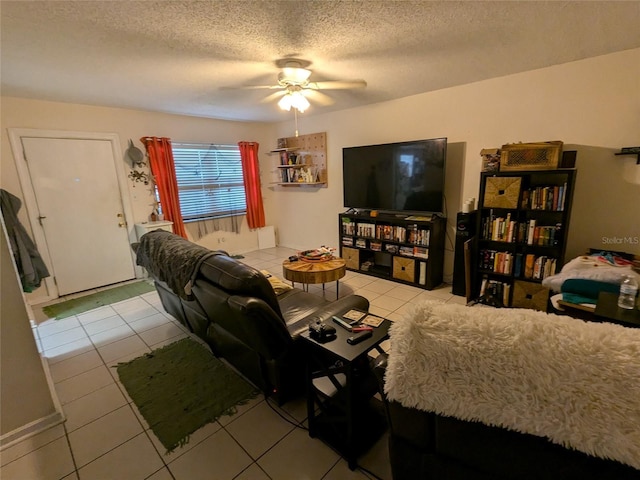 living room featuring ceiling fan, light tile patterned flooring, and a textured ceiling