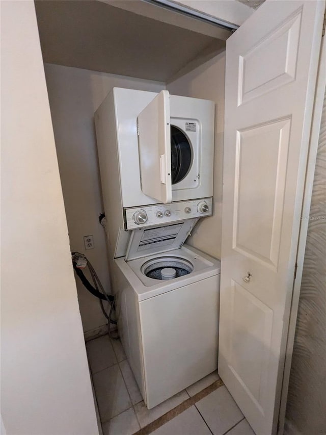 laundry room with light tile patterned flooring and stacked washer / drying machine