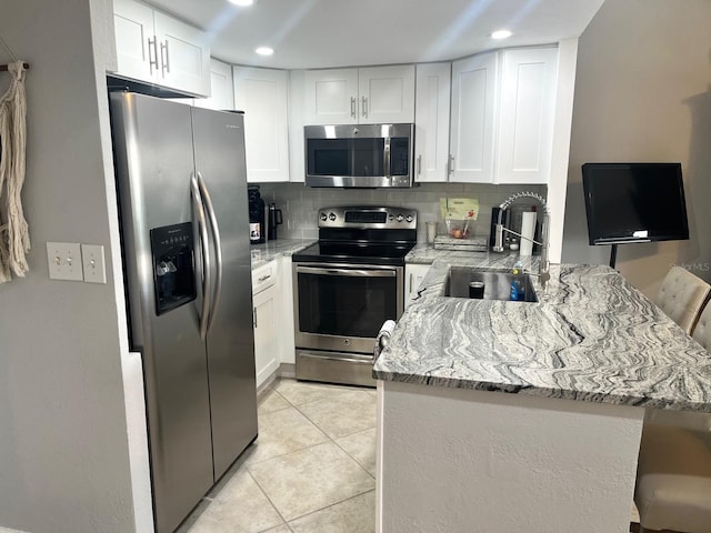 kitchen featuring a breakfast bar, white cabinetry, sink, kitchen peninsula, and stainless steel appliances