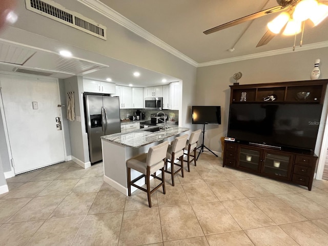 kitchen with crown molding, appliances with stainless steel finishes, light stone countertops, white cabinets, and kitchen peninsula