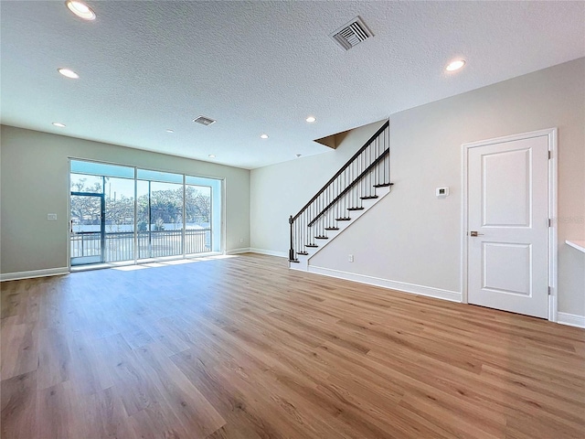 unfurnished living room featuring a textured ceiling and light wood-type flooring