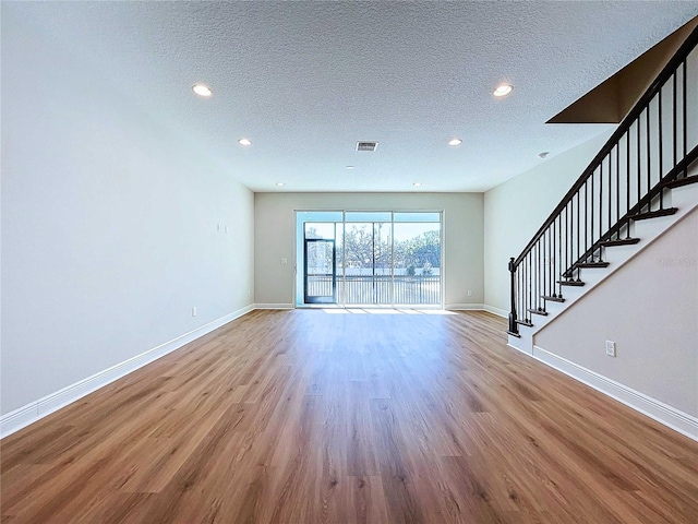 unfurnished living room with light hardwood / wood-style floors and a textured ceiling