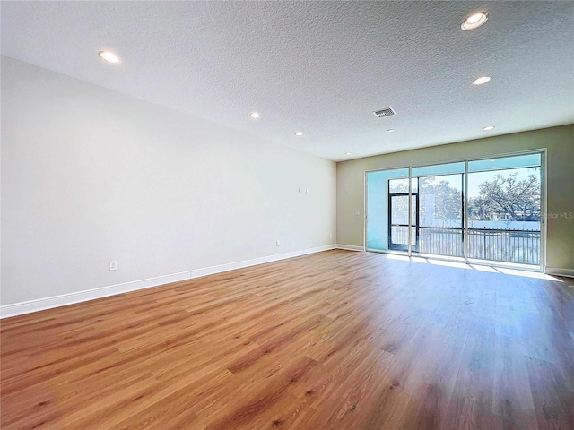 spare room featuring light hardwood / wood-style flooring and a textured ceiling