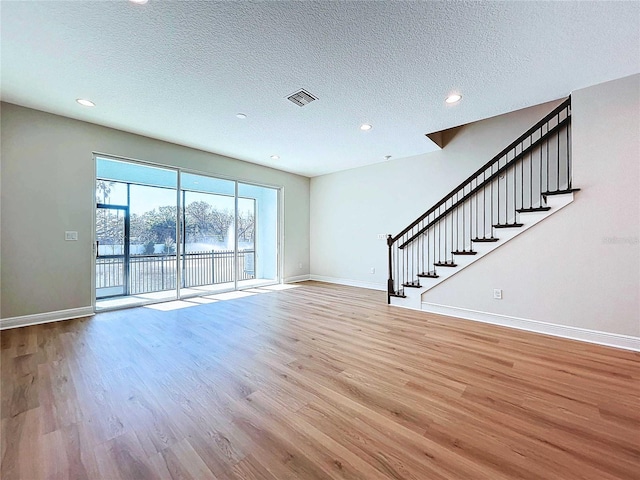 unfurnished living room featuring light wood-type flooring and a textured ceiling