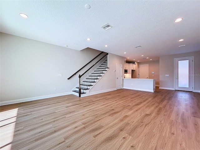 unfurnished living room featuring light wood-type flooring and a textured ceiling