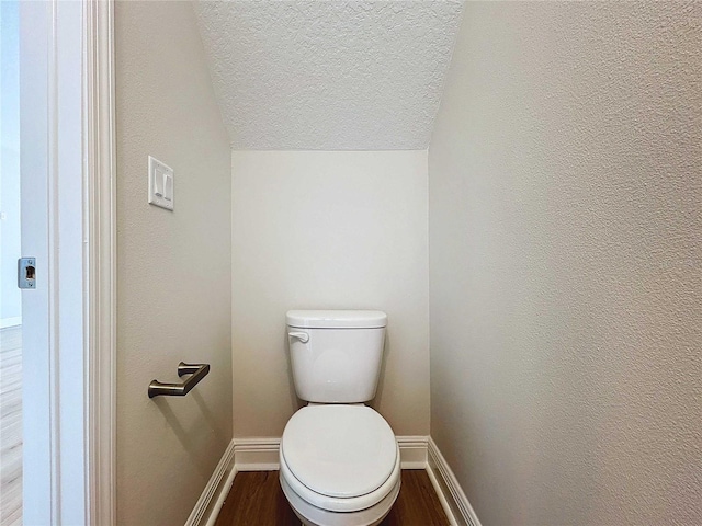 bathroom featuring toilet, wood-type flooring, a textured ceiling, and vaulted ceiling