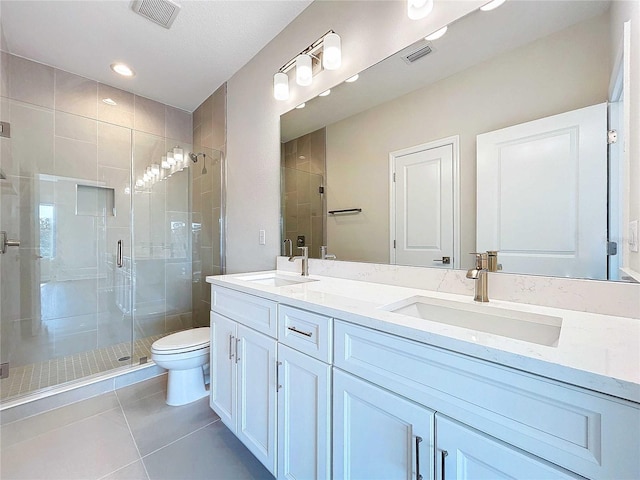 bathroom featuring tile patterned flooring, vanity, a shower with shower door, and toilet