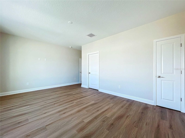 empty room featuring a textured ceiling and hardwood / wood-style flooring