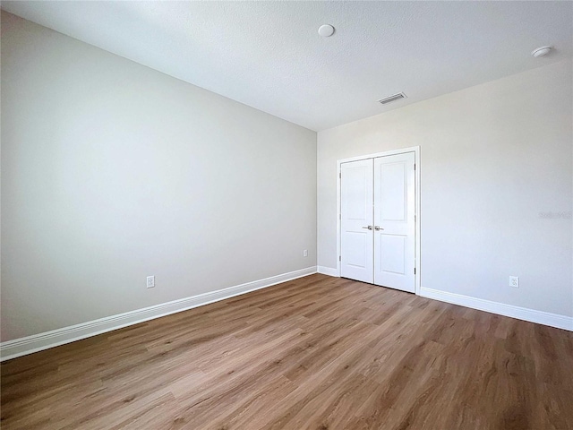 unfurnished bedroom featuring wood-type flooring, a textured ceiling, and a closet