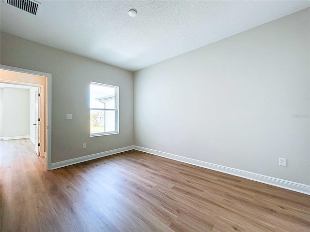 unfurnished room featuring a textured ceiling and light hardwood / wood-style flooring