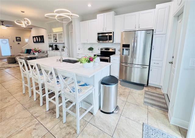 kitchen featuring sink, white cabinets, stainless steel appliances, and decorative light fixtures