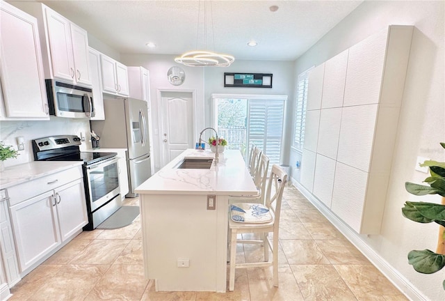 kitchen featuring a kitchen island with sink, sink, white cabinets, and appliances with stainless steel finishes