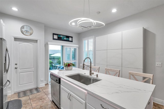 kitchen featuring a kitchen island with sink, sink, decorative light fixtures, white cabinetry, and stainless steel appliances