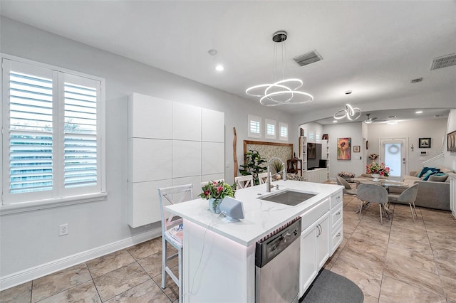 kitchen featuring pendant lighting, sink, stainless steel dishwasher, an island with sink, and white cabinetry