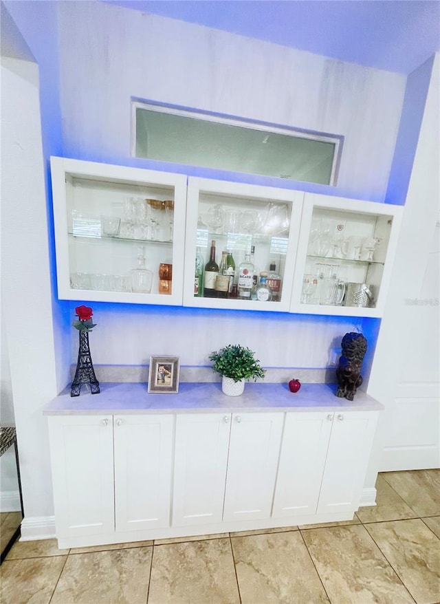 bar with white cabinets and light tile patterned floors