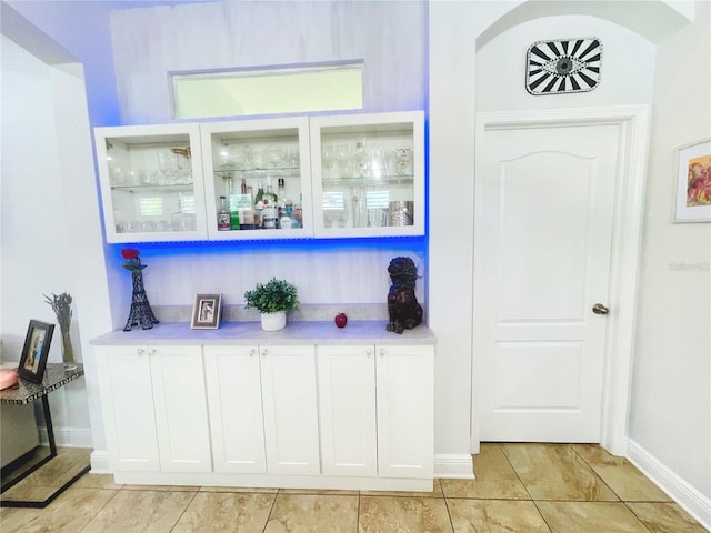 bar with white cabinets and light tile patterned floors