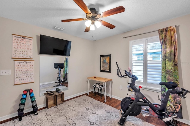 exercise area featuring hardwood / wood-style floors, a textured ceiling, and ceiling fan