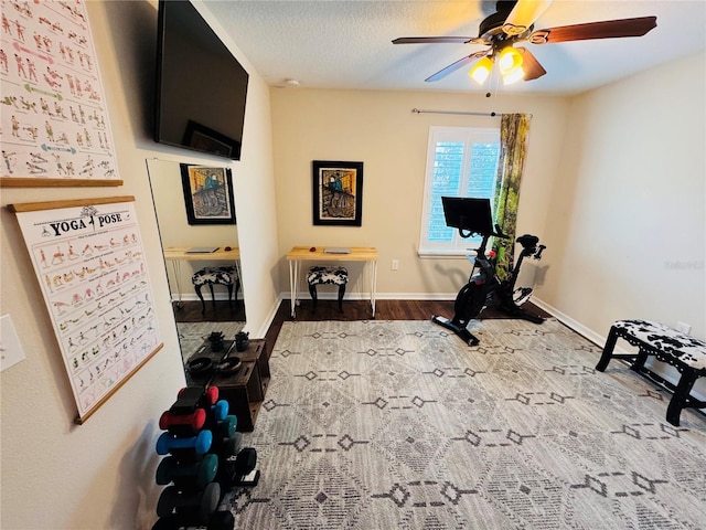 exercise area featuring a textured ceiling, light wood-type flooring, and ceiling fan