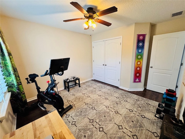 workout room with a textured ceiling, hardwood / wood-style flooring, and ceiling fan