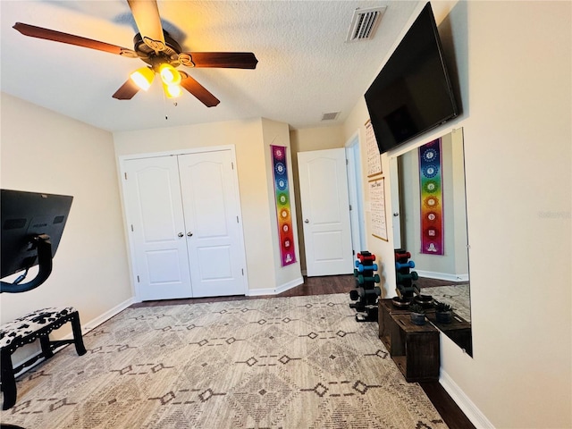 interior space with light wood-type flooring, a textured ceiling, a closet, and ceiling fan