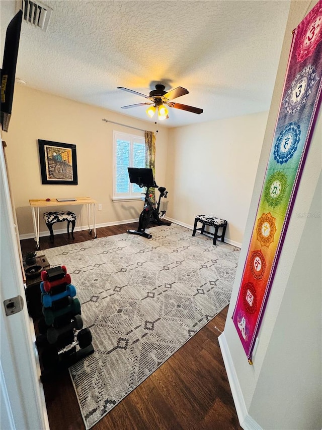 exercise room with a textured ceiling, hardwood / wood-style flooring, and ceiling fan