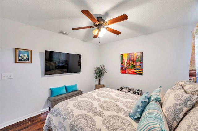 bedroom with a textured ceiling, dark hardwood / wood-style flooring, and ceiling fan