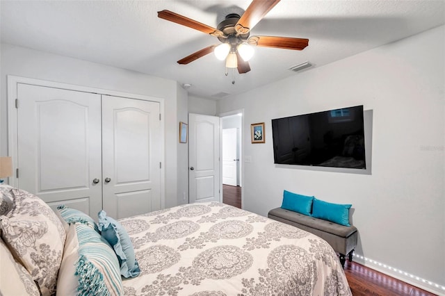 bedroom with dark hardwood / wood-style flooring, ceiling fan, and a closet