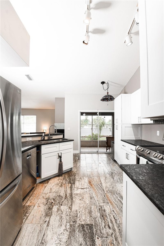 kitchen featuring white cabinetry, ceiling fan, appliances with stainless steel finishes, dark stone counters, and sink