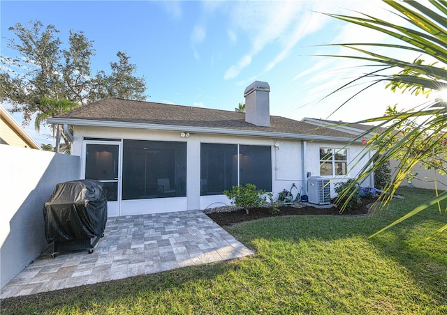 rear view of house featuring central AC, a sunroom, a lawn, and a patio