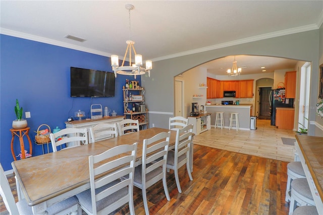 dining space featuring light wood-type flooring, an inviting chandelier, and crown molding