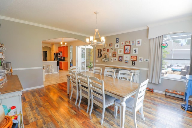 dining area with crown molding, a chandelier, and light wood-type flooring