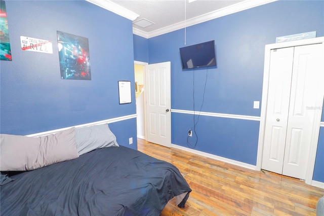 bedroom with a closet, wood-type flooring, and ornamental molding