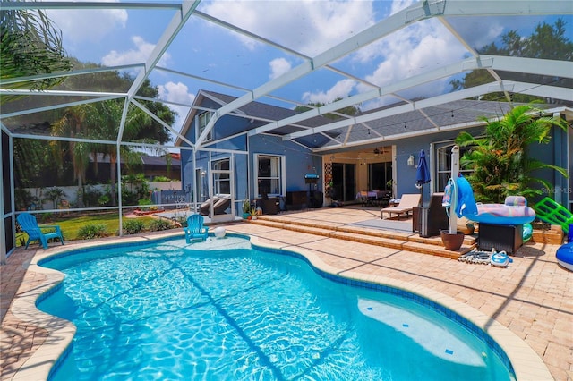 view of pool featuring glass enclosure, ceiling fan, and a patio area