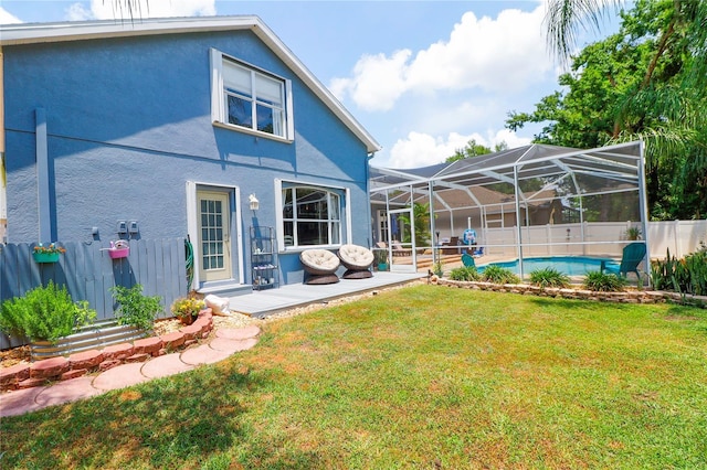 rear view of house with glass enclosure, a patio area, a fenced in pool, and a yard