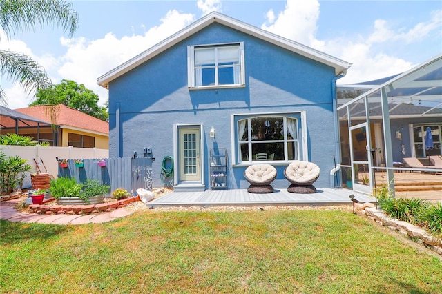 rear view of property with a lanai, a wooden deck, and a yard