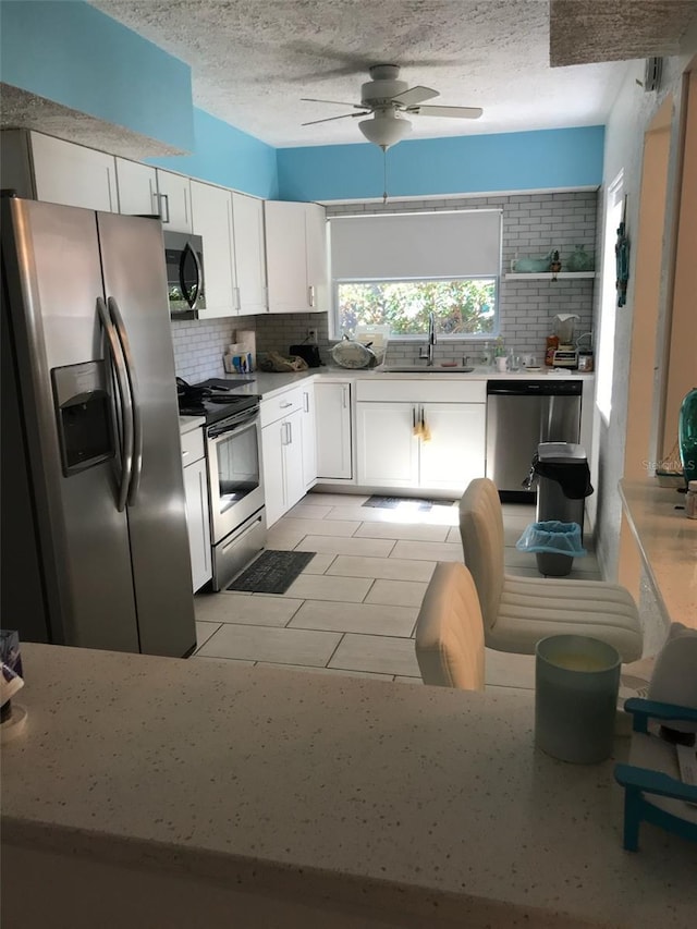 kitchen with stainless steel appliances, tasteful backsplash, sink, and white cabinets