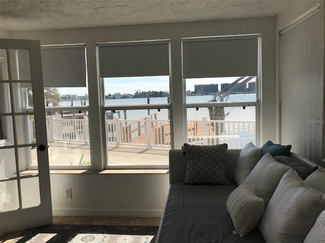 living room with wood-type flooring, a water view, a wealth of natural light, and a textured ceiling